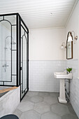 Pedestal washbasin against tiled wall and shower cubicle in bathroom
