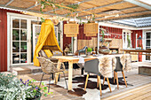 Dining table with classic chairs and rattan sofa with yellow canopy on a covered terrace