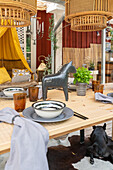 Set dining table with a horse figurine, above it bamboo hanging lamps