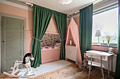 Cubby bed in girl's bedroom with pink walls and green floor-length curtains