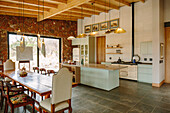 Island counter and dining area with long wooden table in open-plan kitchen