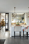 Elegant island counter with designer chairs: Christmas tree in the background
