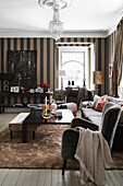 Elegant living room with upholstered furniture, console table and striped wallpaper
