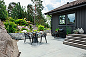 Modern outdoor dining area in grey on terrace next to boulders