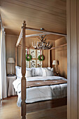 Double bed with wooden frame in wood-panelled bedroom