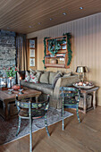 Classic living room with wood panelling in a cabin: painted farmhouse chairs in the foreground