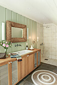 Mirror with wicker frame above long washstand in bathroom