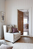 Light grey armchair against white-painted wood panelling in living room