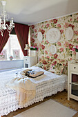 Romantic bedroom with rose-patterned wallpaper, plaster reliefs and crocheted bedspreads