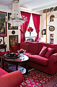Sofa set with cushions, rugs and red curtains in living room