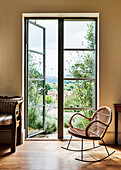 Bamboo rocking chair next to French windows with garden access