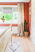 Cactus in basket in bedroom with terracotta-coloured walls