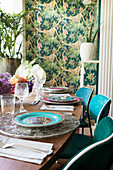 Set, oval dining table in room with jungle-patterned wallpaper