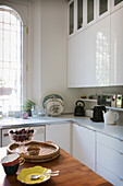 Einbauküche mit weißen Fronten, Glasschale mit Kirschen auf Küchentisch
