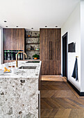 Kücheninsel aus Naturstein und Schränke mit Holzfronten