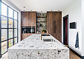 Kücheninsel aus Naturstein und Schränke mit Holzfronten vor Glasschiebeelement