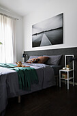 Double bed with anthracite headboard below landscape photo