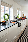 Weiße Küchenzeile mit Arbeitsplatte aus schwarzem Granit vor Fenster