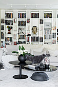 Weißes Wohnzimmer mit Regalwand, Sofa und schwarzem Tischset