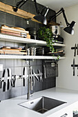 Shelves with wall-mounted lamps and magnetic knife rack above sink