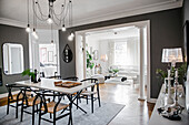 Classic chairs around dining table with marble top below pendant light in room with grey walls