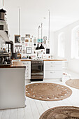 White kitchen with pendant lights, round rugs and floorboards
