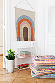 Colourful seat cushions, shelf and tapestry in room corner