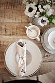 Place setting in natural colours, coffee cup and bouquet on wooden table