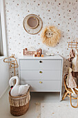 Toys and chest of drawers in nursery with patterned wallpaper