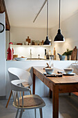 Kleine Küche mit Holztisch, modernen Stühlen und schwarzen Hängeleuchten