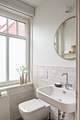 Small, white bathroom with half-height tiled wall and toilet