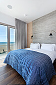 Blue quilt on the bed in the bedroom with sea view
