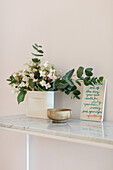 Bouquet of flowers with eucalyptus branches and bowl on console table with marble top