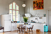White, L-shaped kitchen counters and fridge in converted chapel