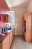 Kitchen base units below pendant light in front of red wall