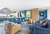 Open-plan interior with blue and white sofas and buff leather armchairs