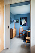 Blick ins Arbeitszimmer mit blau gestrichener Holzverkleidung und Kommode