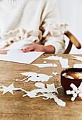 Person making paper tags at wooden table with coffee