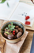 Bowl with walnuts and rosehip branch, book in the background