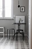 Slender black table and stools on tiled floor