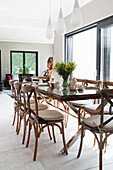 Dining table and chairs below pendant lights next to patio doors in open-plan interior