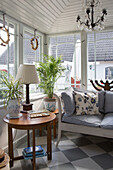 Round table and sofa with striped cushions in the conservatory