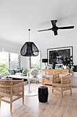 Round dining table with rattan chairs and black rattan lamp in bright room
