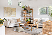White sofas with cushions, shelf and wooden coffee table in bright living room