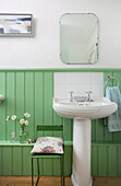 Pedestal sink against green wainscoting in bathroom