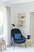 Sitting area with blue armchair, side table and shelving unit