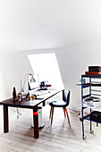 Schlichtes Arbeitszimmer mit Holztisch, Stuhl und Regal, Dachschräge