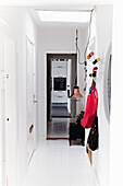 Narrow hallway with white walls, pendant light and colurful decorative elements