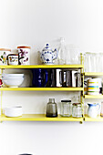 Yellow wall shelf with crockery and glasses in different styles