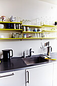 Küchenzeile mit Regalen in Gelb und schwarzer Arbeitsplatte